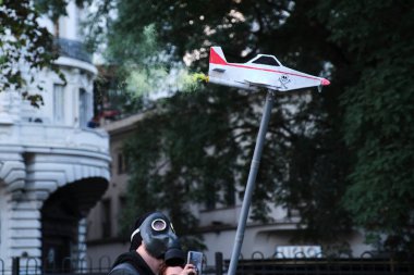 Buenos Aires, Arjantin; 21 Mayıs 2022: Tarım sektöründe GDO ve böcek ilaçlarının kullanımını protesto. Gaz maskesi takan aktivist yeşil duman püskürten bir dezenfekte uçağı taşıyor..