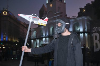Buenos Aires, Arjantin; 21 Mayıs 2022: Tarım sektöründe GDO ve böcek ilaçlarının kullanımını protesto. Gaz maskesi takan aktivist, ilaçlama uçağı taşıyor.
