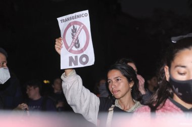 Buenos Aires, Argentina; May 21, 2022: people protesting against the GMO and pesticides in agriculture. Young woman holds a sign against the cultivation of genetically modified HB4 wheat. clipart