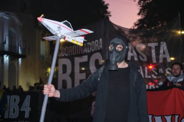 Buenos Aires, Arjantin; 21 Mayıs 2022: Tarım sektöründe GDO ve böcek ilaçlarının kullanımını protesto. Gaz maskesi takan aktivist, ilaçlama uçağı taşıyor.