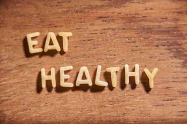 Tahta arka planda alfabe çorbası makarna harfleriyle şekillendirilmiş sağlıklı şeyler ye. Gıda ve sağlık konsepti.