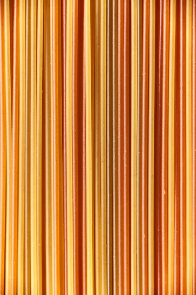 Abstract italian food background, raw colourful vegetable spaghetti filling the frame in a textured design of mixed colors vertical pasta lines.
