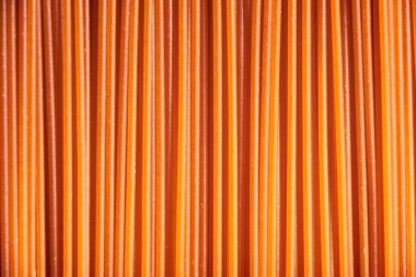 Italian healthy food background, raw sweet bell pepper spaghetti filling the frame in a textured design of red vertical pasta lines.