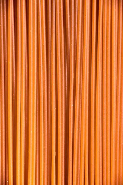 Italian healthy food background, raw sweet bell pepper spaghetti filling the frame in a textured design of red vertical pasta lines.