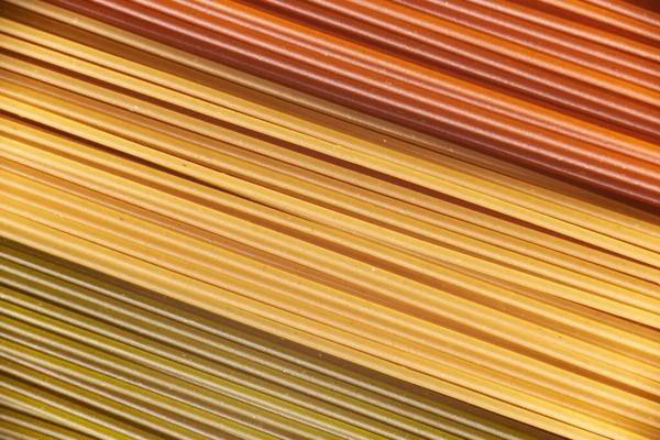 Abstract italian food background, raw colourful vegetable spaghetti filling the frame in a textured design of red, yellow and green diagonal pasta lines.