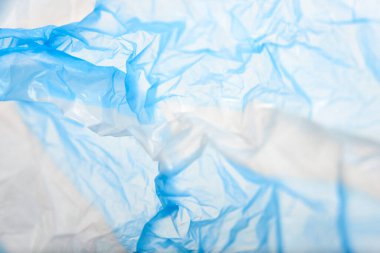 White and blue plastic background, wrinkled single use bag. Concepts: sustainability, recycling, pollution.