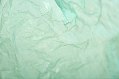 Green plastic background, wrinkled single use bag. Concepts: sustainability, recycling, pollution.