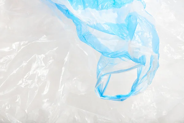 Plastic single use bags. Blue and white wrinkled background. Concepts: sustainability, recycling, pollution.