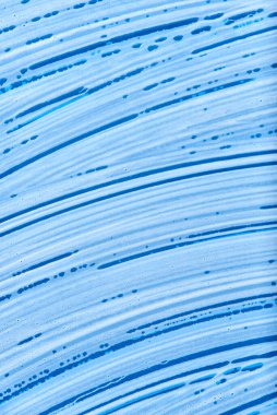 Top view of a blue glass surface covered with soap foam. Monochromatic background without people, concept of cleanliness.