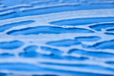 Blue glass surface covered with soap foam. Monochromatic abstract design with shallow depth of field, concept of cleanliness.