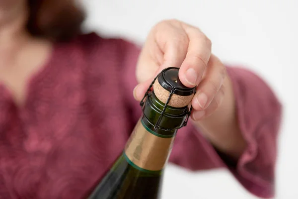 Unrecognizable woman opening a bottle of champagne or cider. Concept of festivity and celebration. Close up image with copy space.