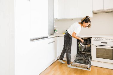 happy young woman doing housework in her kitchen