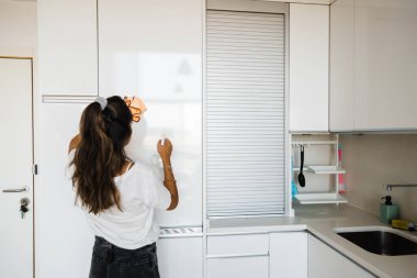 young woman cleaning white and bright kitchen