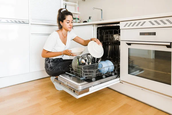 Young single woman putting the dishes in the dishwasher — Foto Stock