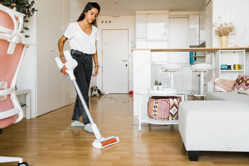 young woman vacuuming her home