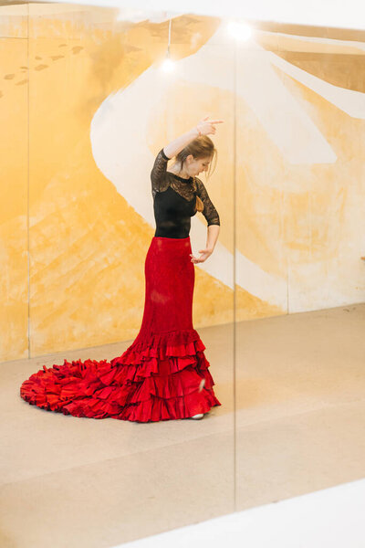 Flamenco woman dancer practicing on a studio with a tail gown
