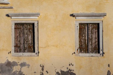 Kapalı kahverengi panjurlu eski duvardaki iki pencere Pellestrina Adası, Venedik lagünü, İtalya