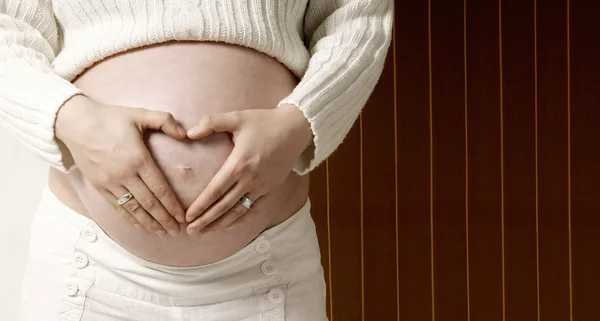 妊娠中の女性の心に形の手で ロイヤリティフリーのストック画像