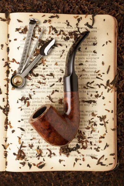 Smoking pipe and pipe tool on a book — Stock Photo, Image