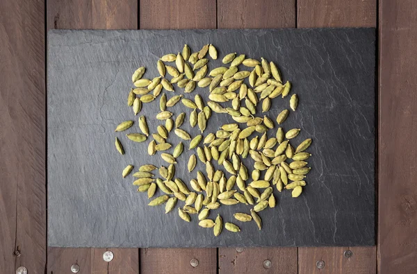 Cardamom seeds scattered on a slate plate — Stock Photo, Image