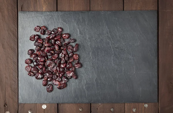 Dry red cranberries on a slate plate with copy space — Stock Photo, Image