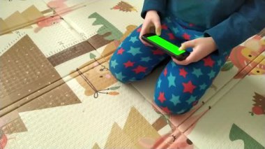 Çocuk yeşil ekranlı akıllı telefondan oyunu oynuyor