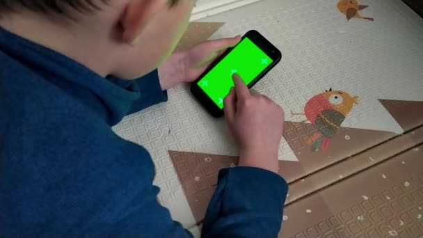 Το αγόρι περνά μέσα από τις σελίδες στο Διαδίκτυο σε ένα smartphone με πράσινη οθόνη — Αρχείο Βίντεο