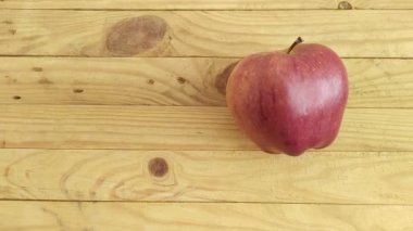 Bir kadının eli ahşap bir masadan kırmızı bir elma alır.