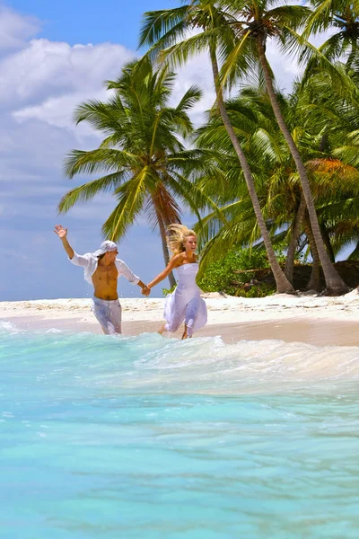 Loving couple runs on a tropical beach — Stock Photo, Image