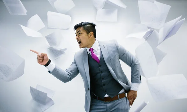 Angry businessman with pile of papers flying on air Royalty Free Stock Images