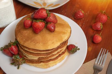 Masada bir tabak sıcak kek ve çilek.
