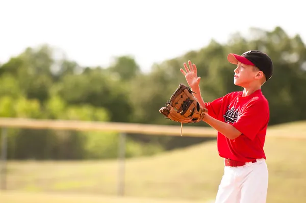 Pequeno jogador de beisebol da liga pegando a bola . Fotos De Bancos De Imagens
