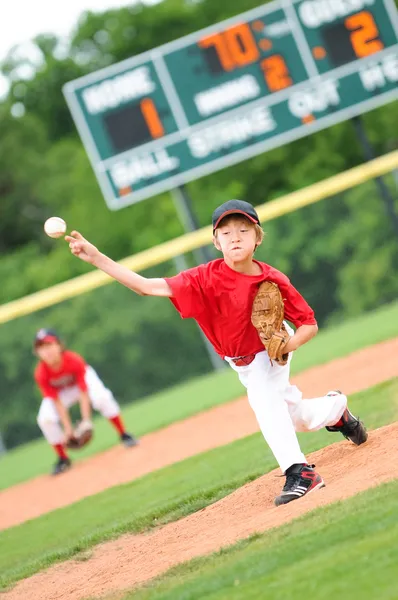 Junge Baseballspielerin wirft den Ball Stockbild