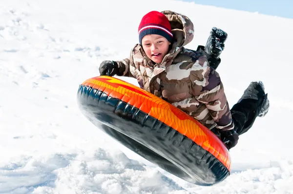 Boy up in the air on a tube in the snow — Stock Photo, Image