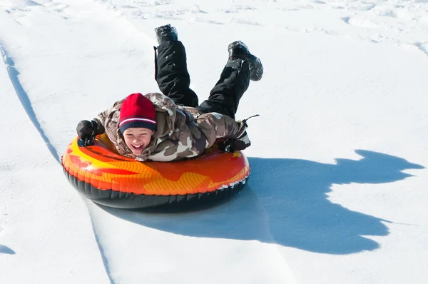 Happy boy sleding on a tube. — Stock Photo, Image