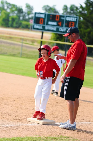 Baseballspieler und Baseballtrainer am ersten Stützpunkt. — Stockfoto