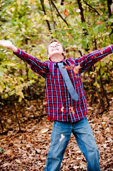Jeune garçon levant les yeux avec des feuilles tombant — Photo