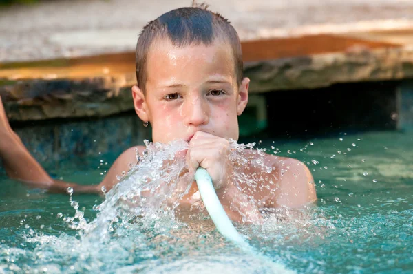 Pojke leker med vattenslang i poolen — Stockfoto