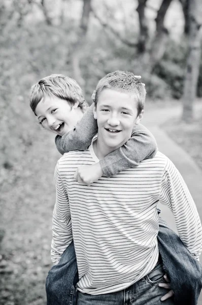 Cute brothers laughing giving piggyback ride — Stock Photo, Image