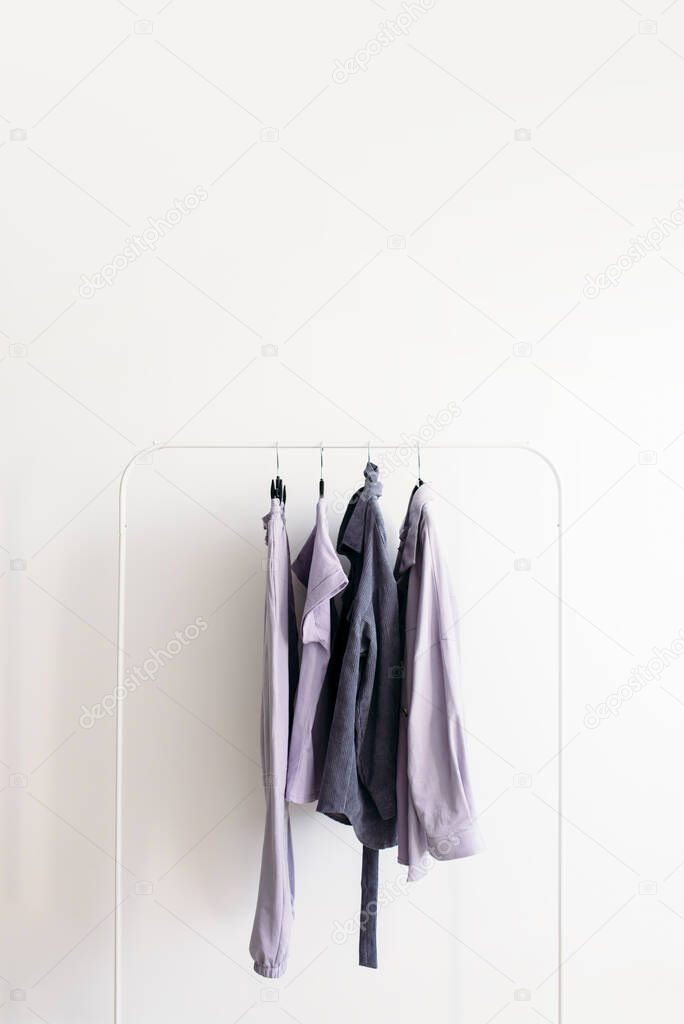 Rack with capsule clothes in gray and pastel lavender colors Minimalism concept