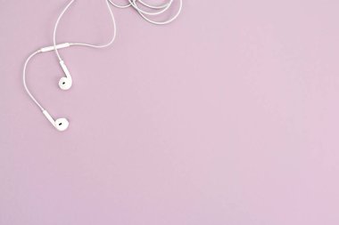 Pastel arka planda beyaz kulaklıklı minimal üst görünüm