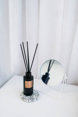 Beyaz bir masada yuvarlak aynalı siyah aroma yayıcı. Rahatla spa konsepti