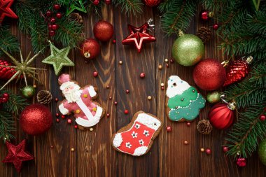 Kahverengi ahşap masa üzerindeki lezzetli Noel kurabiyeleri köknar dalları ve baloncuklar. Geleneksel Xmas zencefilli kurabiye. Üst Manzara. Boşluğu kopyala