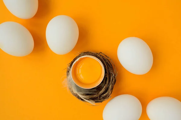 白色的蛋和蛋黄在黄色的背景上筑巢 顶部视图 平躺在床上复活节庆祝活动 — 图库照片