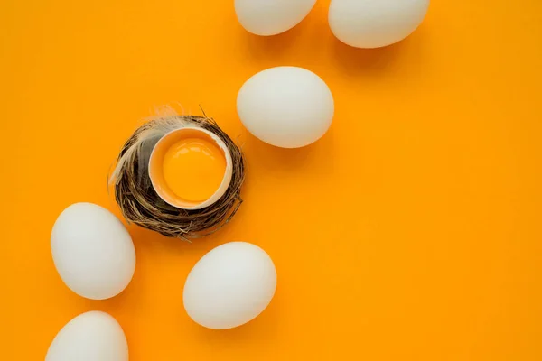 白色的蛋和蛋黄在黄色的背景上筑巢 顶部视图 平躺在床上复活节庆祝活动 — 图库照片