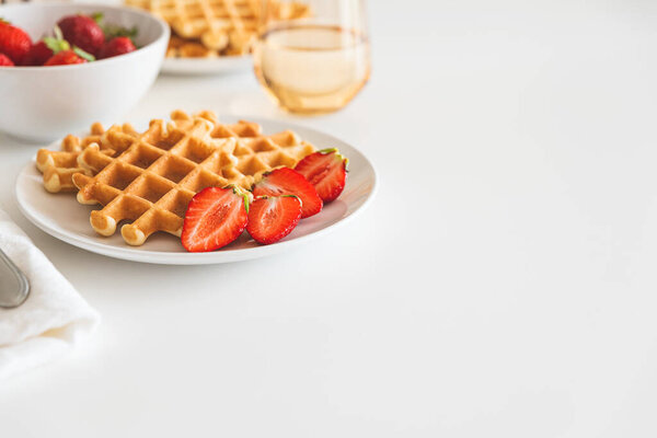 Belgian waffles with strawberry on white plate. Breakfast food concept. Copy space