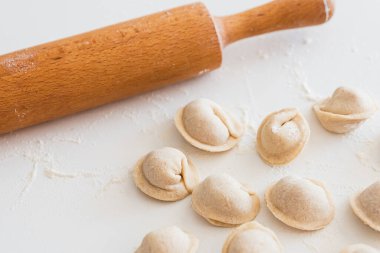 Beyaz masada pişmemiş ev yapımı pelmeni. Pelmeni, ravioli veya etli hamur tatlısı yapma süreci
