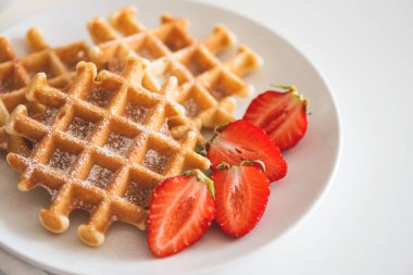 Çilekli Belçika waffle 'ları ve beyaz tabakta pudra şekeri. Kahvaltı konsepti. Boşluğu kopyala