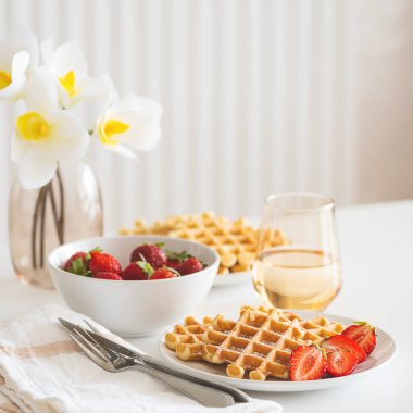 Çilekli Belçika waffle 'ları ve beyaz tabakta pudra şekeri. Kahvaltı konsepti.