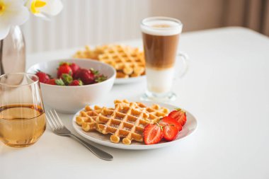 Çilekli Belçika waffleları ve beyaz tabakta kahve. Kahvaltı konsepti. Boşluğu kopyala
